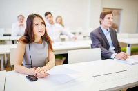 Photograph of adults seated in a classroom setting, appearing attentive and engaged in a learning or training session
