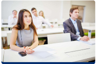 Photograph of adults seated in a classroom setting, appearing attentive and engaged in a learning or training session