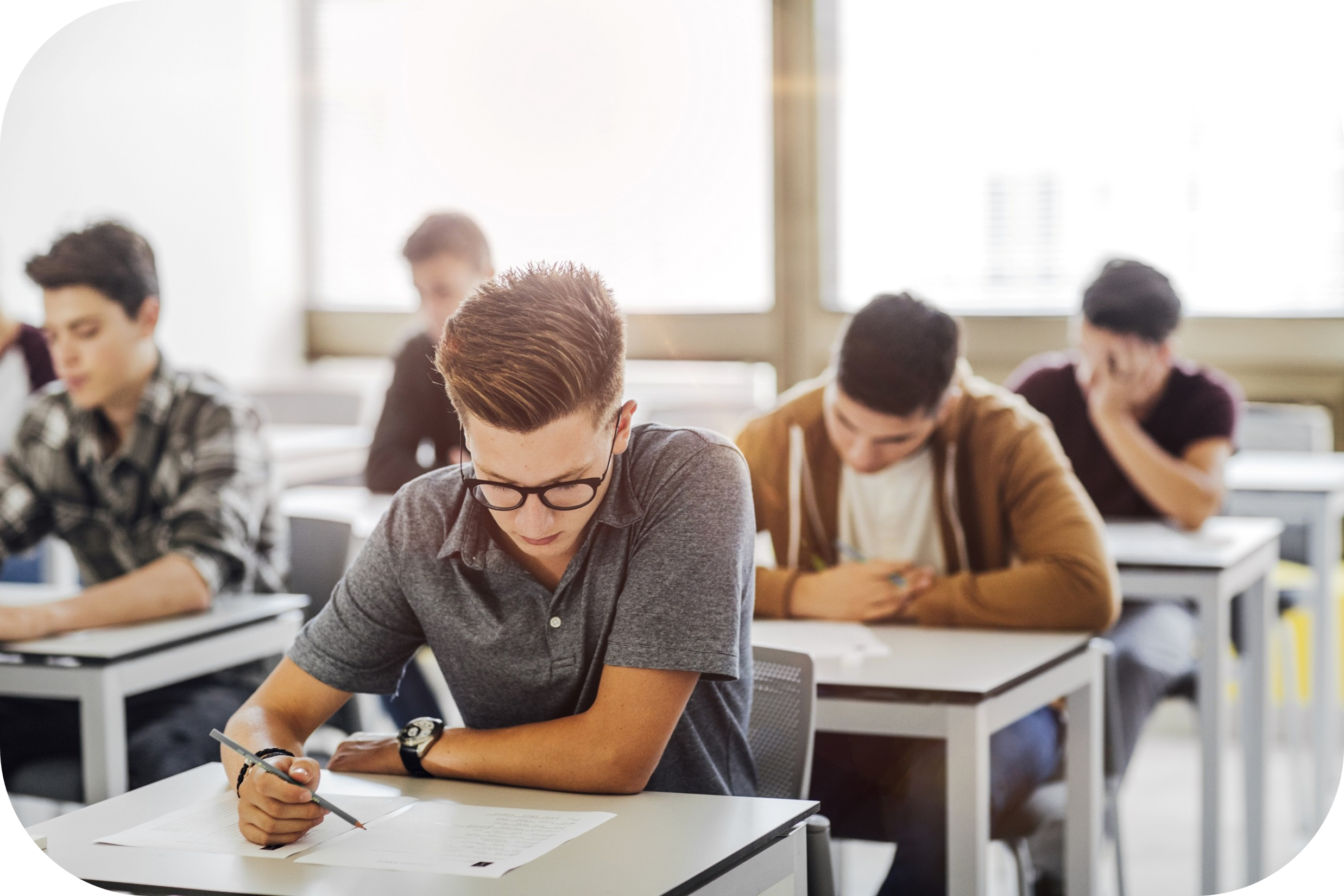 Students seated at individual desks, focused on an exam in a classroom rounded corners